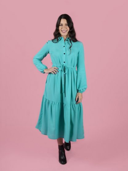 Woman wearing the Lyra Shirt Dress sewing pattern by Tilly and the Buttons. A dress pattern made in light to medium weight woven fabrics, featuring a button front opening, side seam pockets, long billowy sleeves with elasticated cuffs, side seam pockets and gathered skirt with a trendy tier.