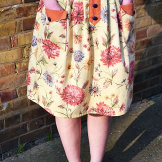 Woman wearing the Pocketful Skirt sewing pattern by Stitched in Wonderland. A pleated skirt pattern made in light to medium weight woven fabrics, featuring a high waist, front patch pockets and a false button placket on the front.
