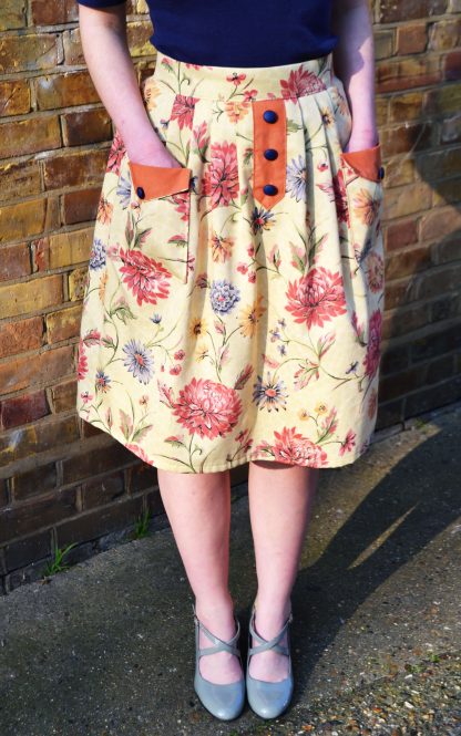 Woman wearing the Pocketful Skirt sewing pattern by Stitched in Wonderland. A pleated skirt pattern made in light to medium weight woven fabrics, featuring a high waist, front patch pockets and a false button placket on the front.