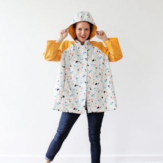 Woman wearing the Whitney Raincoat sewing pattern by Amy Nicole. A raincoat pattern made in waterproof or water resistant fabrics, featuring raglan sleeves, in-seam pockets and a roomy hood.