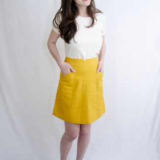 Woman wearing the Crestwood Skirt sewing pattern by Fig and Needle. A skirt pattern made in light to medium weight fabrics such as, denim, linen, poplin, quilting cottons, twill or sateen fabrics, featuring a snug fit, knee length finish, large front pockets and back zipper.