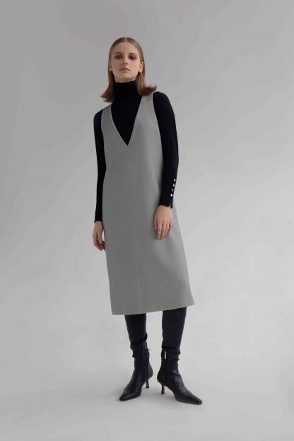 Woman wearing the Stacy Dress sewing pattern by Vikisews. A sleeveless dress pattern made in wool suiting, cotton, tweed, fine coating, gabardine, sturdy velvet, denim or jacquard fabrics, featuring a semi fit, bust darts, in-seam pockets, deep V-neck and below knee length.