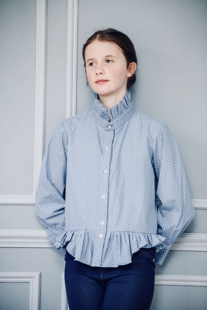 Child wearing the Shirt to Child/Teen Tobermory Top sewing pattern by Greyfriars and Grace. A blouse pattern made in pre-loved shirt fabrics, featuring a ruffle collar, button front closure, ruffle hem and buttoned cuff.