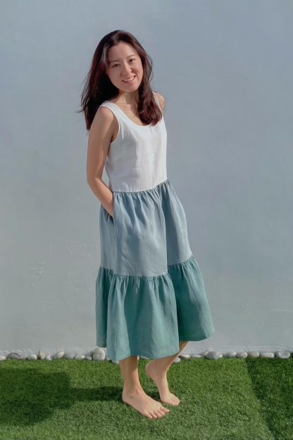 Woman wearing the Kirra Dress pattern from Liola Patterns on The Fold Line. A sleeveless dress pattern made in rayon, crepe, linen, denim, cotton, cotton lawn or silk fabrics, featuring a relaxed fit bodice with bust darts, in-seam pockets, mid-calf length, deep skirt tier and scoop neckline.