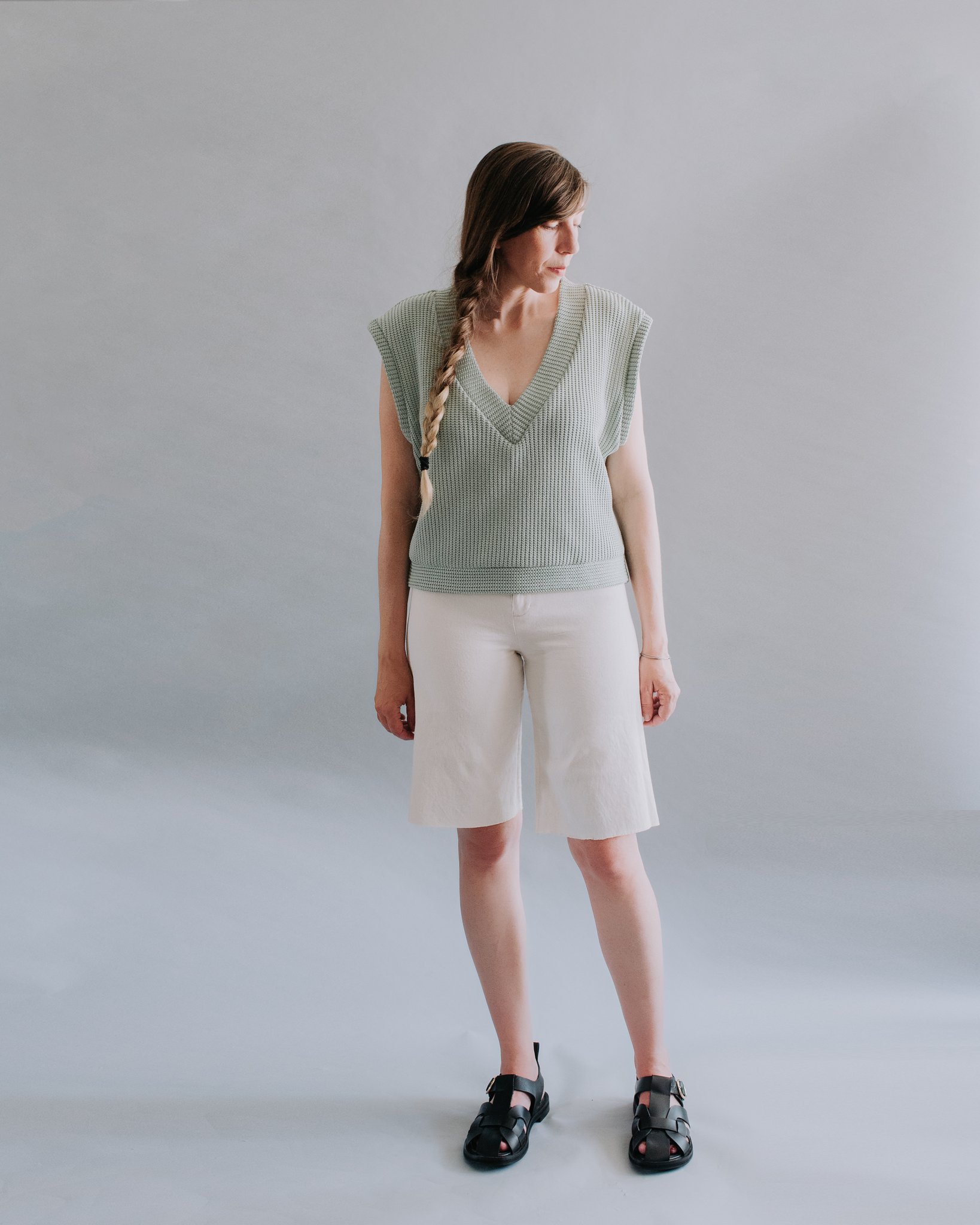Woman wearing the Pierce Vest sewing pattern from Ensemble on The Fold Line. A sleeveless top pattern made in cotton jersey, linen jersey, sweatshirt fleece, scuba knit, double knit, sweater knit or French terry fabrics, featuring a loose fit, deep V-neck, oversized armholes, and ribbed neck, arm and waist bands.