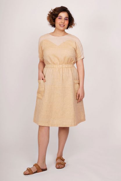 Woman wearing the Valo Dress sewing pattern from Named on The Fold Line. A dress pattern made in non-stretch, medium weight fabrics such as linen fabrics, featuring an elasticated waist, large patch pockets, relaxed-fit, heart-shaped yoke with a scoop neck at the front and a V-neck at the back and grown on short sleeves