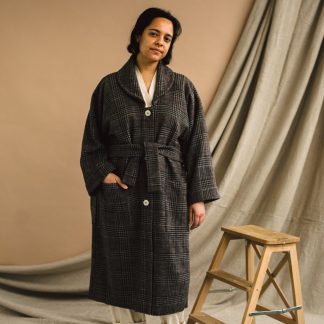 Woman wearing the Unisex ZW Coat sewing pattern from Birgitta Helmersson on The Fold Line. A semi fitted blouse pattern made in mid to heavy weight wool or heavy weight cotton drill fabrics, featuring an oversized silhouette, batwing sleeve, round collar, patch pockets, front button closure and waist tie.