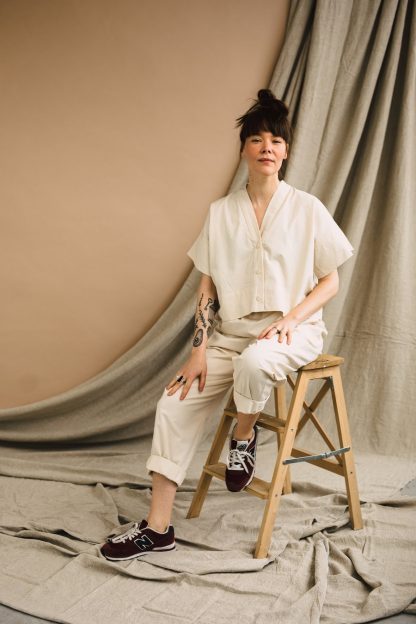 Woman wearing the ZW Cropped Shirt sewing pattern from Birgitta Helmersson on The Fold Line. An oversized cropped shirt pattern made in woven linen or cotton fabrics, featuring dropped shoulders, V-neck band, button front closure and short sleeves.