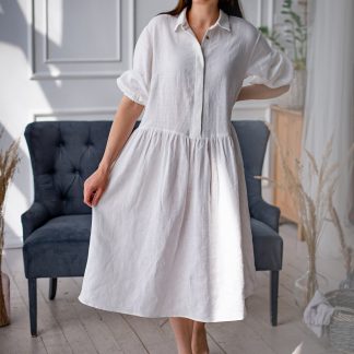 Woman wearing the Cecilie Dress sewing pattern from Kates Sewing Patterns on The Fold Line. A dress pattern made in linen or cotton fabrics, featuring a loose fit, dropped waistline, below knee length, bust darts, button placket, shirt collar, back yoke, gathered skirt, voluminous sleeves with elasticated cuffs.