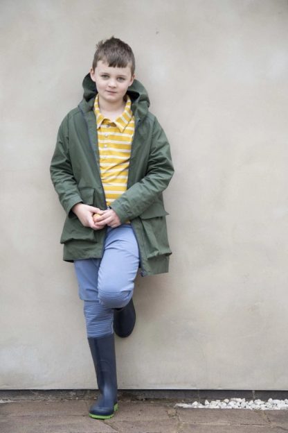 Child wearing the David Raincoat sewing pattern from Bobbins and Buttons on The Fold Line. A unisex raincoat pattern made in laminated cotton, polyurethane, coated cotton, cotton drill or denim fabrics, featuring instructions for making a lined version of the David Raincoat.