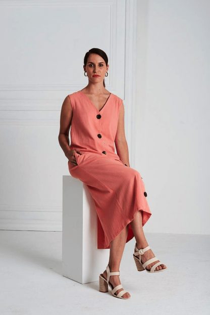 Woman wearing the Lea Dress pattern from Pattern Sewciety on The Fold Line. A sleeveless dress pattern made in cotton, cotton blends, linen, linen blends, chambray or silk fabrics, featuring front button closure, bust darts, V-neck, waist seam, in-seam pockets and skirt vent.