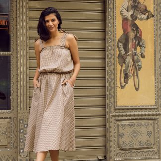 Woman wearing the Amelie Dress sewing pattern from The Patterns Room on The Fold Line. A dress pattern made in flowing woven or knit fabrics, featuring an elasticated chest and waist, relaxed fit, side seam pockets, no closures, tied shoulder straps and midi length.