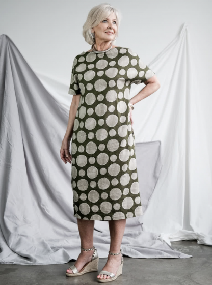 Woman wearing the Melba Dress sewing pattern from Style Arc on The Fold Line. A dress pattern made in Ponte, rugby knit, crepe or light wool fabrics, featuring a mid-length, pull-on style with slight cocoon shape, boat neck, extended shoulder line, short sleeves and in-seam pockets.