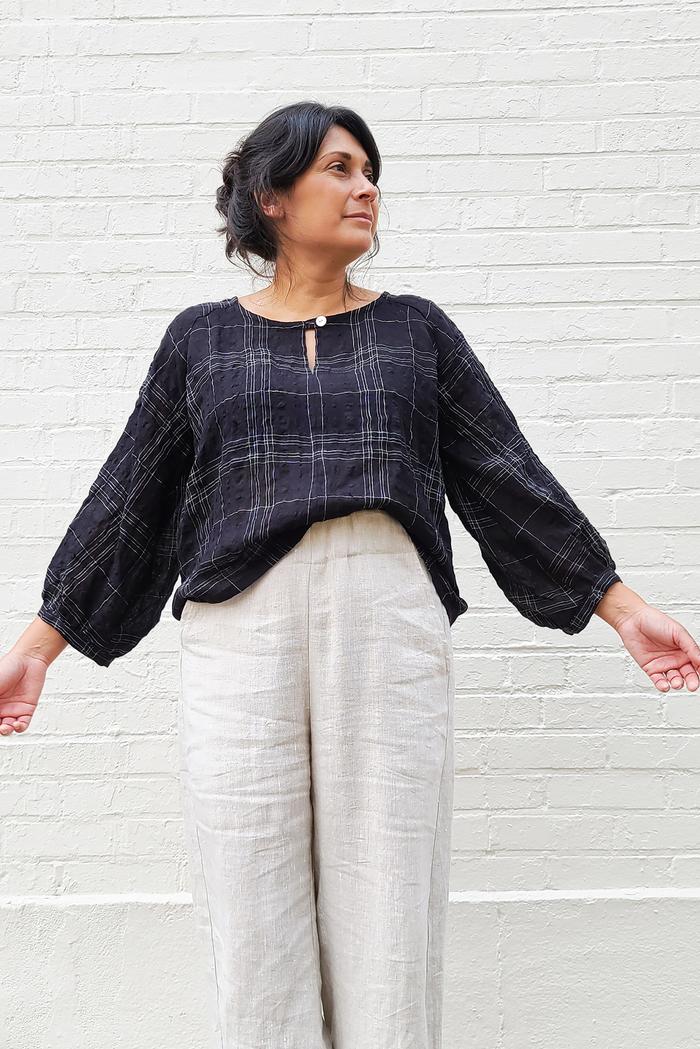 Woman wearing the Remy Raglan Gathered Sleeve Expansion Top sewing pattern from Sew House Seven on The Fold Line. A top pattern made in rayon’s, viscose or cotton fabrics, featuring a boat neck line with button and loop closure, relaxed fit and bracelet length raglan gathered sleeves.