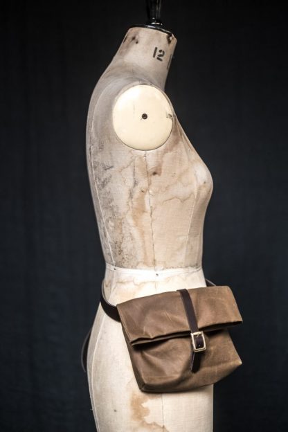 Mannequin showing the Field Belt pattern from Merchant and Mills on The Fold Line. A waist bag pattern made in oilskin, dry oilskin or cotton canvas fabrics, featuring a leather waist belt with buckle, fold-over fabric top and second strap with buckle closure.