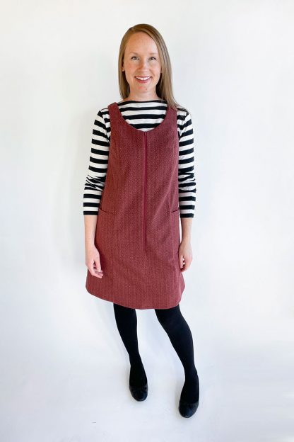 Woman wearing the Georgie Pinafore sewing pattern from Jennifer Lauren Handmade on The Fold Line. A pinafore pattern made in denim, corduroy, wool, cotton ticking or poplin/broadcloth fabrics, featuring a semi-fit, V neckline, exposed centre front zip, side pockets and just above knee length.