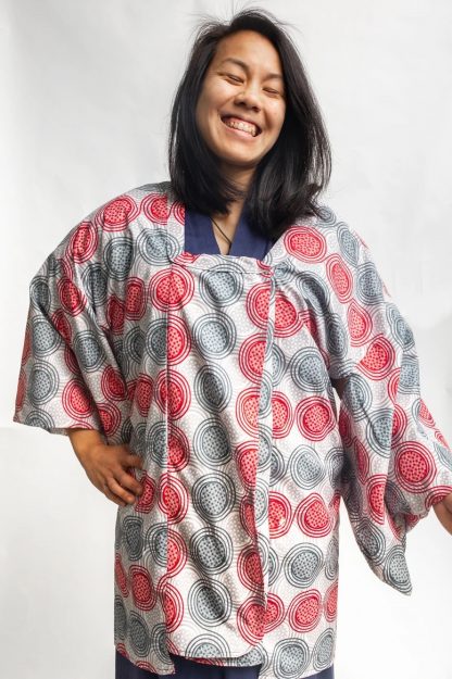 Woman wearing the 143 Japanese Michiyuki sewing pattern from Folkwear on The Fold Line. A robe/jacket pattern made in rayon or silk crepe fabrics, featuring a ¾ length, low, square neckline, double-breasted front opening, robe-style sleeves, narrow neck band with mitred corners, decorative covered buttons, snap fasteners and a hidden pocket in the front seam.