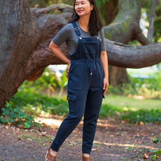Woman wearing the Varzim Overalls sewing pattern from Itch to Stitch on The Fold Line. A dungarees pattern made in sweatshirt fleece with elastane or ponte fabrics, featuring a drawstring waist, adjustable shoulder straps, chest, back and side leg pockets, slight tapered legs and a relaxed fit.