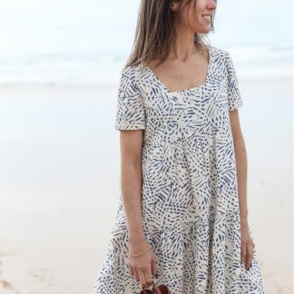 Woman wearing the Astree Dress sewing pattern from Atelier Scammit on The Fold Line. A dress pattern made in batiste, crêpe, double gauze or light denim fabrics, featuring a trapezium neckline at the front and a V at the back, short sleeves and above knee length.