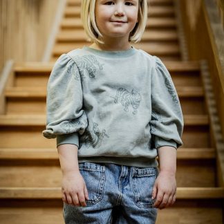 Child wearing the Child/Teen Minnie Top sewing pattern from Fibre Mood on The Fold Line. A jumper pattern made in French terry, sweatshirting or velvet jersey fabrics, featuring a round neckline, 3/4 length puffed sleeves, relaxed fit, ribbed neckline, hem, and wrist cuffs.