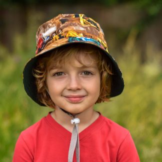 Child wearing the Sandcastle Bucket Hat sewing pattern from Waves & Wild on The Fold Line. A sun hat pattern made in non-stretch light/medium weight woven fabrics, featuring a reversible style, bucket shaped with wide brim.
