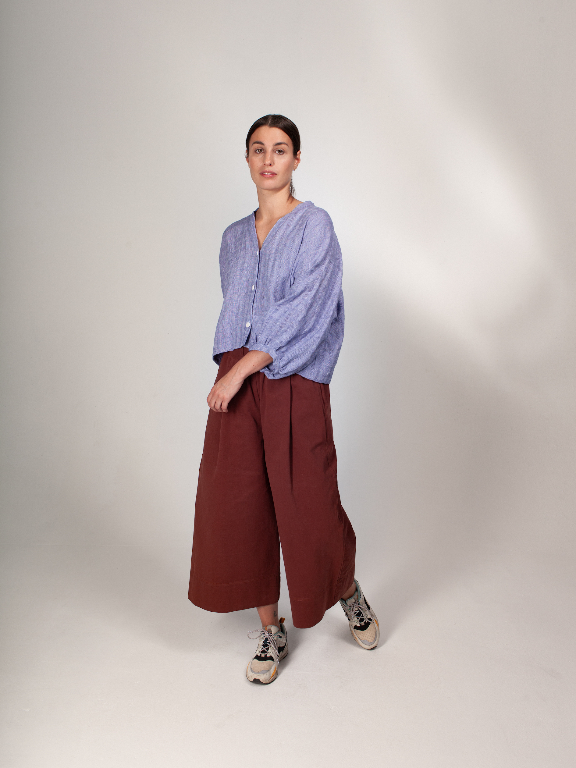 Woman wearing the ZW Block Pant sewing pattern from Birgitta Helmersson on The Fold Line. A wide legged, relaxed fitting trouser pattern made in medium-heavy weight woven cotton and linen or light-mid weight wool fabrics, featuring a waistband with inserted elastic, concealed in-seam pockets at the front and patch pockets at the back.