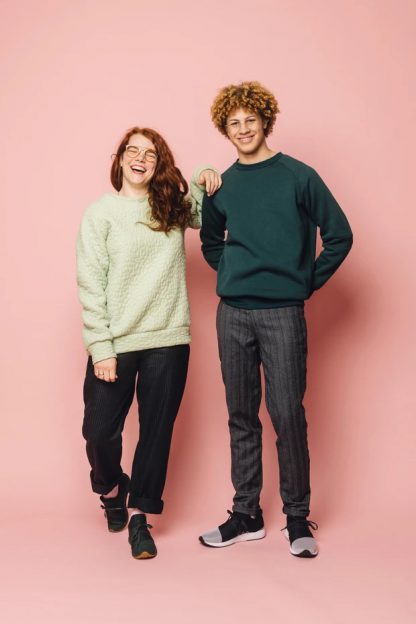Man and women wearing the Maggi Sweater sewing pattern from Melilot on The Fold Line. A unisex sweater pattern made in ponte, double knit, sweatshirt fleece, french terry, jersey or sweater knit fabrics, featuring a relaxed fit, raglan sleeves, cuff, neck and hem bands, full length sleeves plus shorter or longer length.