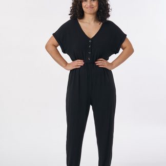 Woman wearing the Nasima Jumpsuit sewing pattern from Sew Over It on The Fold Line. A jumpsuit pattern made in cotton jersey, bamboo, viscose, cotton/elastane or cotton/polyester/spandex jersey blends fabrics, featuring grown on sleeves with short cuffs, V-neck, button-front relaxed fitting bodice, elasticated waist, and full length trousers.