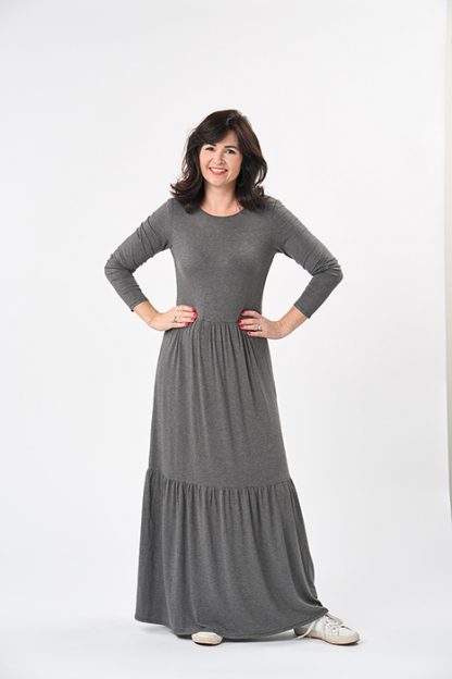 Woman wearing the Nomi Dress sewing pattern from Sew Over It on The Fold Line. A knit dress pattern made in viscose or bamboo jersey, French terry or lightweight cotton jersey fabrics, featuring a crew neckline, long sleeves, gathered skirt that falls just below the knee plus another gathered tier to a maxi dress length.