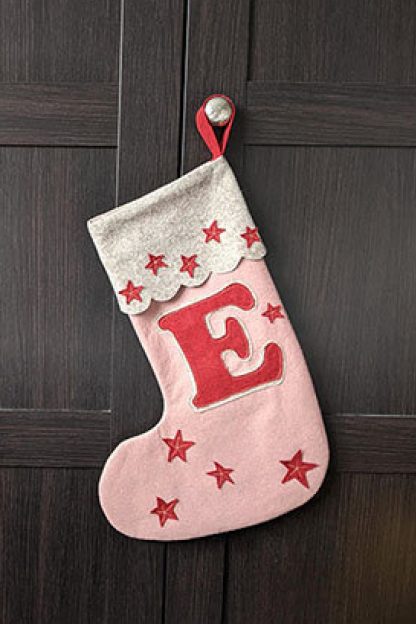 Image showing the Christmas Stocking sewing pattern from Pattern Paper Scissors on The Fold Line. A Christmas stocking pattern made in felt fabrics, featuring stocking silhouette, embroidered stars, letter, contrast cuff and fabric loop.