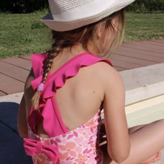 Child wearing the Children's Poéma Swimsuit pattern from Etoffe Malicieuse on The Fold Line. A lined swimsuit pattern made in swimsuit fabric such as lycra with four way stretch, featuring a rounded back, crossed straps with flounces, shoulder flounces, low leg rise, and V-neck.