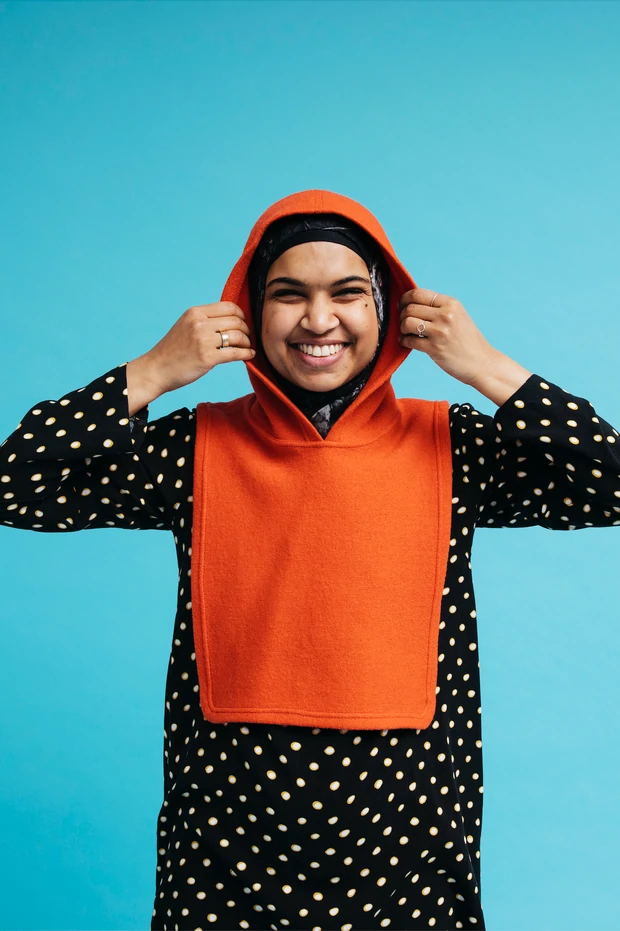 Woman wearing the Knut Hood sewing pattern from Melilot on The Fold Line. A hood with bib pattern made in woven or knit wool fabrics, featuring a front and back bib with attached hood.