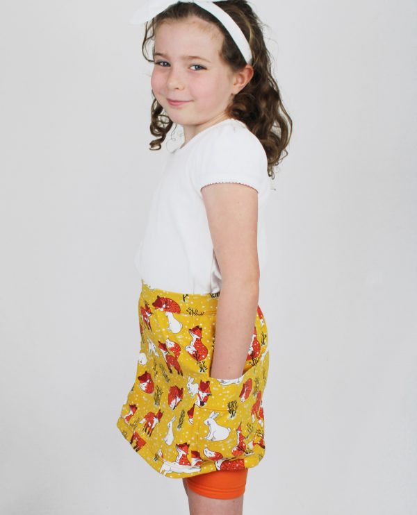 Child wearing the Meadow Skort sewing pattern from Ruth Maddock Makes on The Fold Line. A skort pattern made in stretch jersey fabrics, featuring a pair of above knee leggings with mini skirt attached at the waistband and side patch pockets.