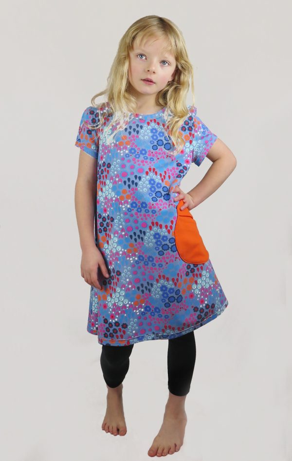 Child wearing the Children's Playtime Swing Dress sewing pattern from Ruth Maddock Makes on The Fold Line. A dress pattern made in jersey fabrics, featuring a pull over the head style, round neck, set–in short sleeves, patch pockets and straight hem.