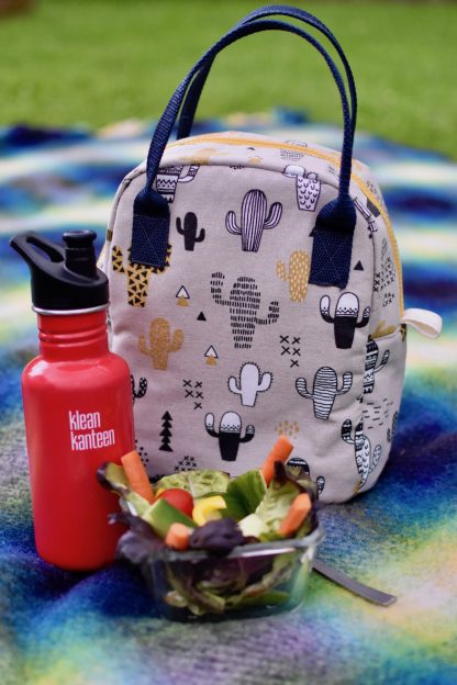 Photo showing the Cool Time Lunch Bag sewing pattern from Waves & Wild on The Fold Line. A lunch bag pattern made in canvas, twill, denim, PUL, ripstop or laminated cotton fabrics, featuring a zip closure and internal bottle pocket.