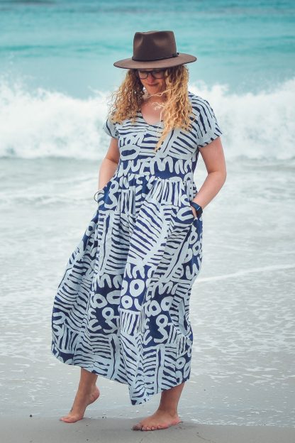 Woman wearing the Kinjarling Dress sewing pattern from Waves & Wild on The Fold Line. A dress pattern made in cotton poplin, cotton lawn or linen fabrics, featuring a relaxed pull-on style, midi length, V-neck, slanted pockets and short grown on sleeves.