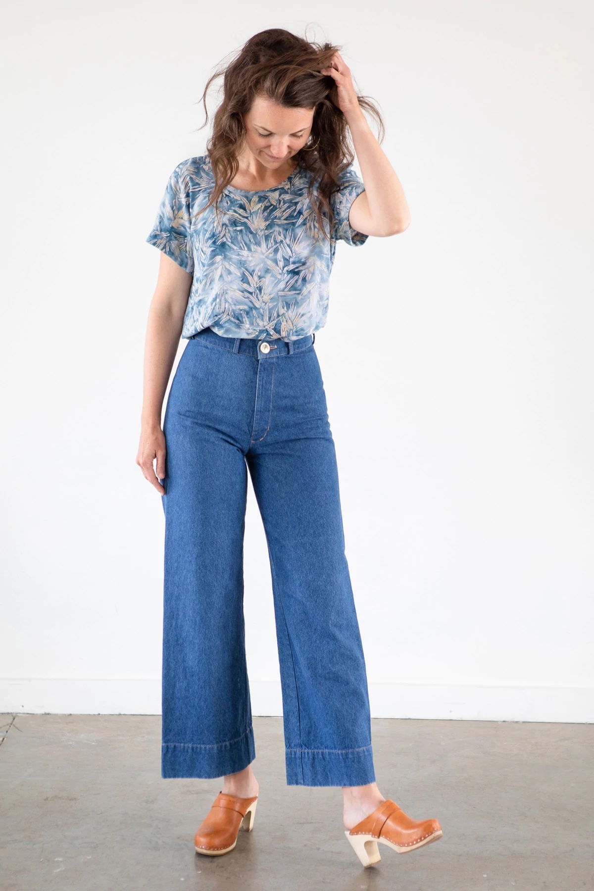 Woman wearing the Coram Top sewing pattern from Allie Olson on The Fold Line. A blouse pattern made in rayon/linen blends, rayon challis, tencel, crepe de chine or georgette fabrics, featuring a loose-fit, raglan sleeves, bust and shoulder darts, sleeve cuffs and curved dolphin hem.