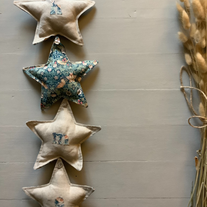 Photo showing the Star Garland sewing pattern from Lasenby on The Fold Line. A star Garland pattern made in canvas, linen, Tana lawn, quilting cotton, twill, duck, denim, and thin tweed fabrics, featuring a star template and appliqué lettering template.