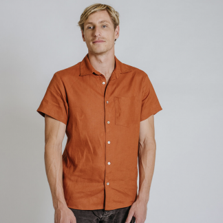 Man wearing the Men's Finch Button Up Shirt sewing pattern from Common Stitch on The Fold Line. A unisex shirt pattern made in linen fabrics, featuring short sleeves, front button closure, collar, scoop back hem and boxy silhouette.