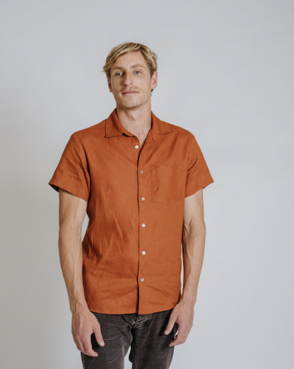 Man wearing the Men's Finch Button Up Shirt sewing pattern from Common Stitch on The Fold Line. A unisex shirt pattern made in linen fabrics, featuring short sleeves, front button closure, collar, scoop back hem and boxy silhouette.
