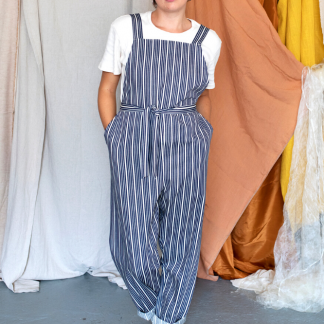 Woman wearing the Greta Dungarees sewing pattern from Made My Wardrobe on The Fold Line. A dungaree pattern made in denim, corduroy, chambray, heavy linen or cotton twill fabrics, featuring an easy fit, deep pockets, shoulder straps and adjustable waist tie.