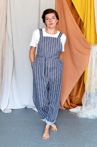 Woman wearing the Greta Dungarees sewing pattern from Made My Wardrobe on The Fold Line. A dungaree pattern made in denim, corduroy, chambray, heavy linen or cotton twill fabrics, featuring an easy fit, deep pockets, shoulder straps and adjustable waist tie.