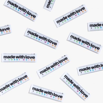 Photo showing 'Made With Love and Swear Words' Woven Labels from Kylie & The Machine on The Fold Line. A washable, durable and non-scratchy fabric label featuring the words' Made With Love and Swear Words', all ready to be sewn into your handmade clothes.
