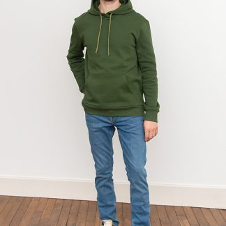 Man wearing the Men's Rainbow Hoodie sewing pattern from I AM Patterns on The Fold Line. A hoodie pattern made in sweatshirt, interlock, neoprene or French terry fabrics, featuring kangaroo pockets, full length sleeves, hood with drawstring, ribbed cuffs and hem.