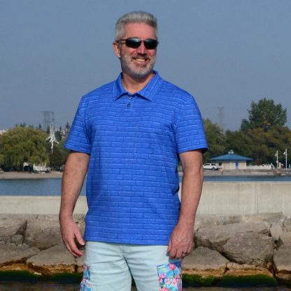 Man wearing the Men's Draper Polo Shirt sewing pattern from Wardrobe by Me on The Fold Line. A polo shirt pattern made in single jersey, activewear knit or fancy knit fabric fabrics, featuring a relaxed fit, classic polo collar, placket with two buttons, front pocket, side vents and short sleeves.