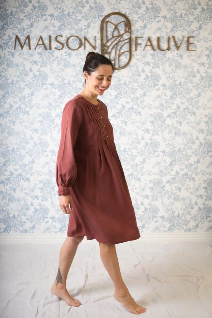 Woman wearing the Atlas Dress sewing pattern from Maison Fauve on The Fold Line. A dress pattern made in linen, light cotton, embroidered cotton, chambray, tencel, viscose twill or silk fabrics, featuring front pleats and button placket bodice, long gathered sleeves with pleated cuff, knee length, back yoke and relaxed fit.