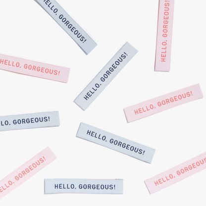 Photo showing 'Hello Gorgeous' Woven Labels from Kylie & The Machine on The Fold Line. A washable, durable and non-scratchy fabric label featuring the words 'Hello Gorgeous' all ready to be sewn into your handmade clothes.