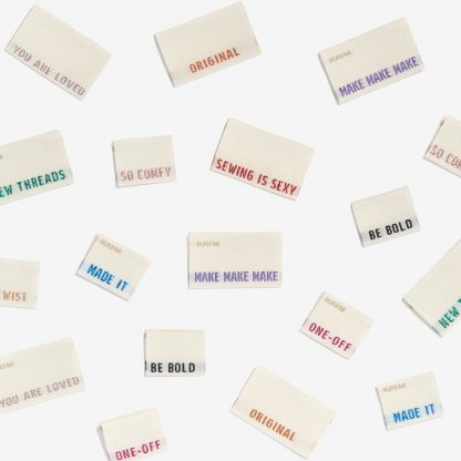 Photo showing numerous woven labels, with a unique word or phrase on each Woven Label from Kylie & The Machine on The Fold Line. A washable, durable and non-scratchy fabric label all ready to be sewn into your handmade clothes.