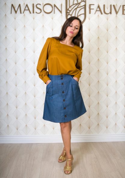 Woman wearing the Kim Skirt sewing pattern from Maison Fauve on The Fold Line. A skirt pattern made in linen, tencel, fine denim, viscose twill, chambray or cotton fabrics, featuring slightly raised waist, elasticated back, front patch pockets, button front closure, knee length hem and A-line silhouette.