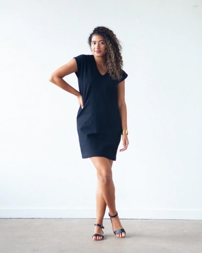 Woman wearing the Lodo Dress sewing pattern from True Bias on The Fold Line. A dress pattern made in medium weight stable knit fabrics, featuring a straight fit through the waist and hips, slightly tapered hem to create a subtle cocoon shape, V neck at centre front, extended cap sleeves and above knee length hem.
